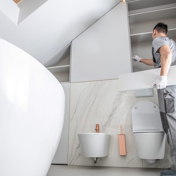 New Bathroom Interior Finishing. Caucasian Men in His 30s Assembling Modern Cabinets. Home Interior Remodeling Theme.